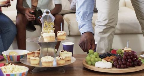 African American Family Gathering Reaching for Cupcakes and Fruit Platter at Birthday Celebration