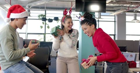Multicultural team exchanging holiday gifts in bright modern office for festive teamwork