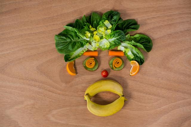 A creative face made of fruits and vegetables on a wooden surface. This playful arrangement promotes healthy eating and adds a fun twist to nutrition education.