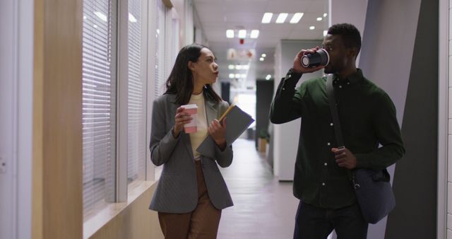 Two Professionals Walking in Office Corridor with Coffee - Download Free Stock Images Pikwizard.com