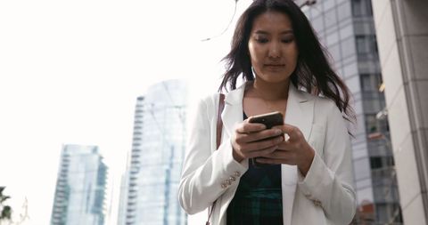 Fashionable asian woman using smartphone in cityscape