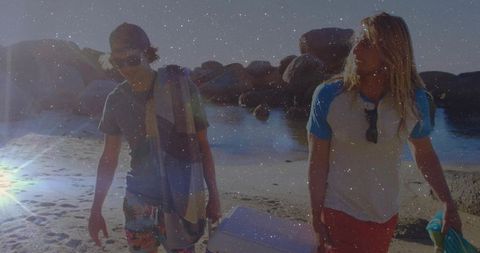 Young Men Enjoying Beach Day Carrying Cooler Along Scenic Shore