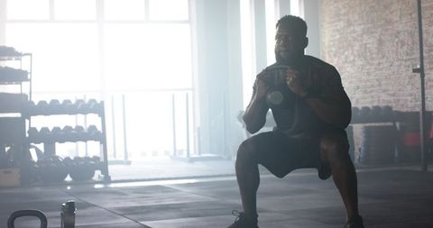 Focused athlete performing weighted squats in bright gym