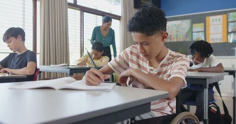 Diverse Classroom with Boy in Wheelchair Engaged in Writing Activity - Download Free Stock Images Pikwizard.com