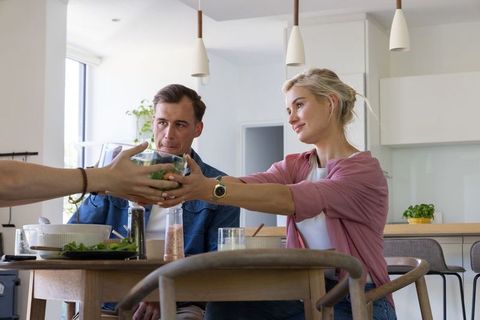 Young african couple receiving salad bowl at modern kitchen table sharing meal together