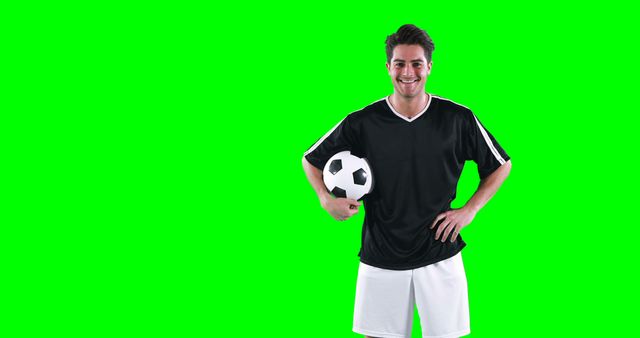 Smiling football player holding a football against green screen