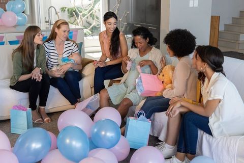 Diverse friends celebrating in living room with gifts and balloons