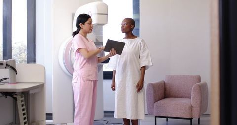 Radiology Technician Consulting Patient Before Mammogram Using Tablet in Modern Clinic