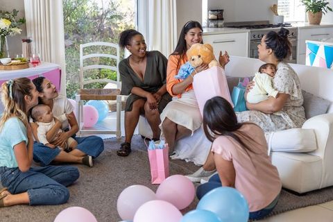Diverse friends celebrating baby shower with gifts and decorations