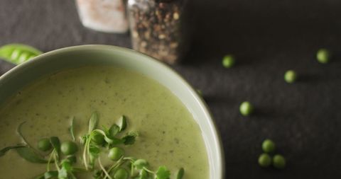 Close-up of creamy pea soup in bowl with fresh herbs garnish