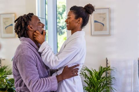 African american couple sharing morning intimacy in bathrobes by sunlit bathroom window