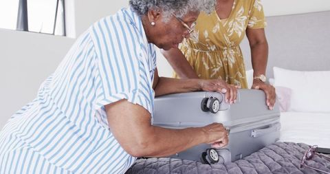 Senior African American Friends Packing Suitcase for Vacation