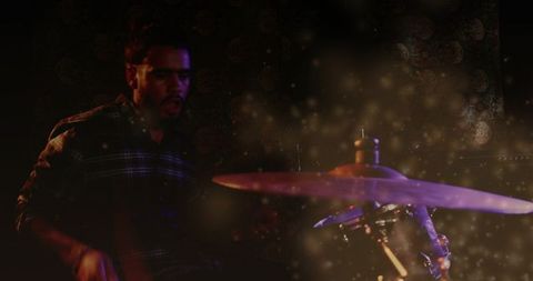 Male drummer playing on intimate stage with purple lighting, cymbal strike and smoky haze
