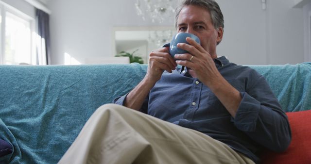 Middle-aged man relaxing on couch with coffee cup at home - Download Free Stock Images Pikwizard.com