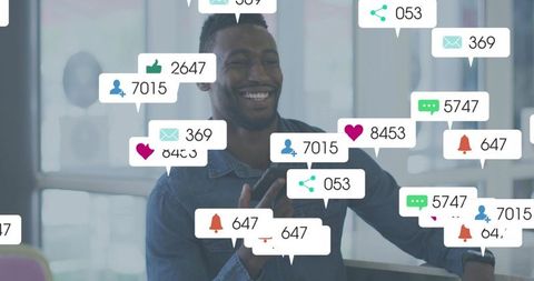 Smiling man interacting with social media notifications on mobile in modern workspace