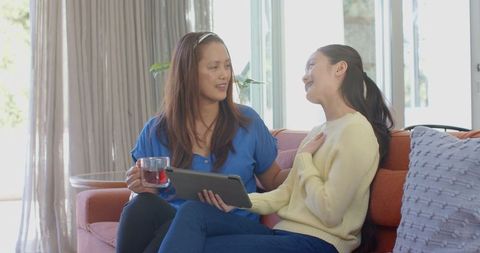 Mother and Daughter Bonding on Cozy Couch with Tablet
