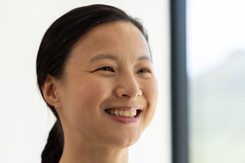 Mature woman smiling in natural light, relaxed headshot with braid and soft expression