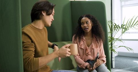 Colleagues Socializing in Modern Office Lounge with Coffee and Tablet