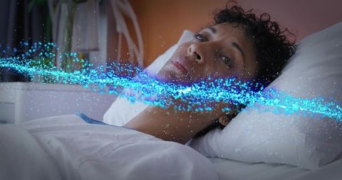 Mature woman lying in bed gazing upward with dreamy blue digital light overlay