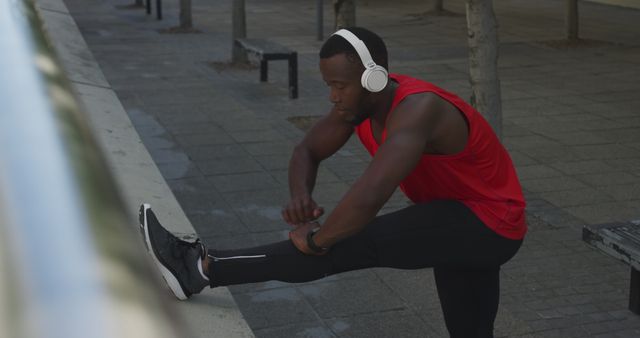 Man Stretching Outdoors with Headphones in Red Tank Top - Download Free Stock Images Pikwizard.com