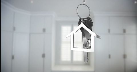 Silver house-shaped keychain hanging in modern white kitchen