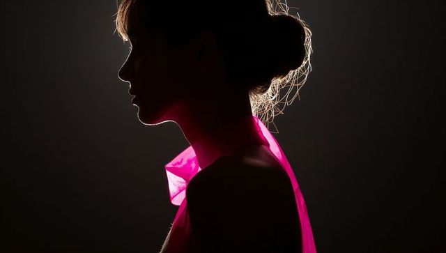 Elegant silhouette of woman with translucent hot-pink scarf and glow