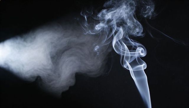 Ethereal smoke plume curling and billowing on black backdrop for abstract design