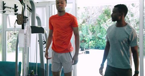Two young men working out indoors in bright modern gym