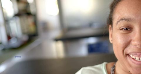 Smiling young woman close-up with soft bokeh communal room background and copy space warm natural li