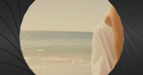 Woman Facing Calm Ocean Waves Through Spiral Frame at Tranquil Beach