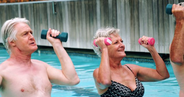Elderly man and woman engaging in water aerobics with hand weights in an outdoor pool. Ideal for promotions related to senior fitness, healthy lifestyles, physical therapy, exercise programs for elderly, and aquatic fitness marketing materials.