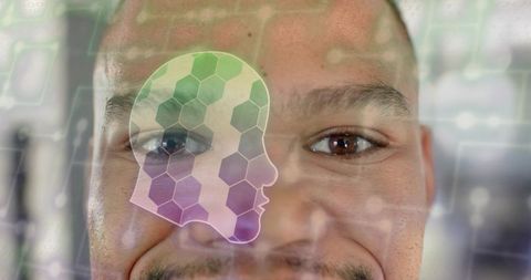 Smiling man looking at holographic biometric head silhouette with hexagon interface overlay