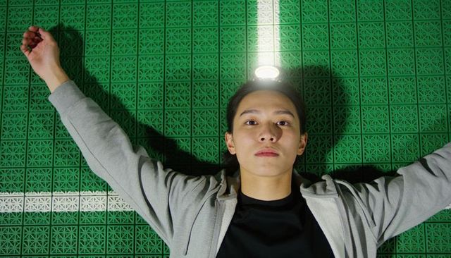 Teen lying on green sports flooring with led halo lighting and patterned tiles solitary athlete