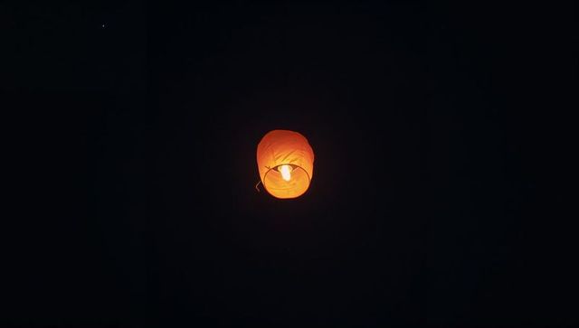 Tranquil Orange Sky Lantern Rising in Night Sky