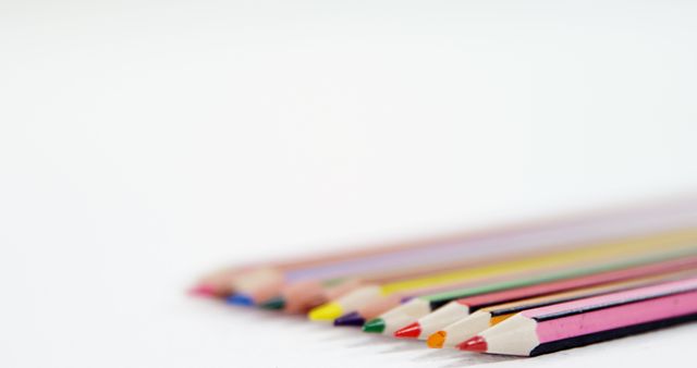 Closeup of various colored pencils placed in a row on a white background. Ideal resources for themes involving art, school, creativity, and education. Perfect for usage in promotional materials for art supplies, educational articles, stationery brands, or creative projects.