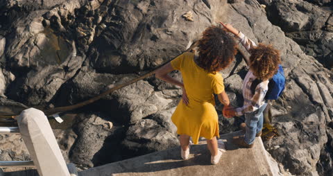 Mother and Son Exploring Rocky Seaside on Sunny Day