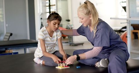 Therapist Assisting Girl in Cerebral Palsy Rehabilitation Therapy