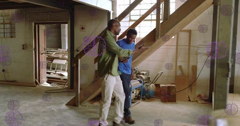 Contractors Discussing Wooden Staircase in Workshop Using Tablet for Renovation Plan