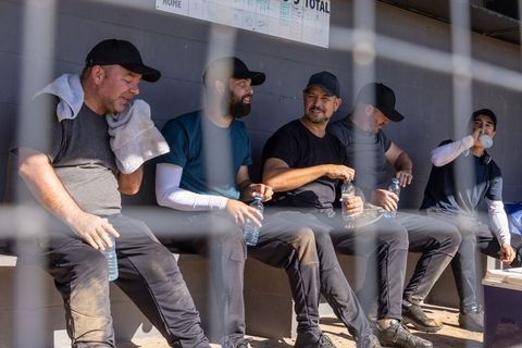Baseball teammates resting in dugout, drinking water and chatting between innings