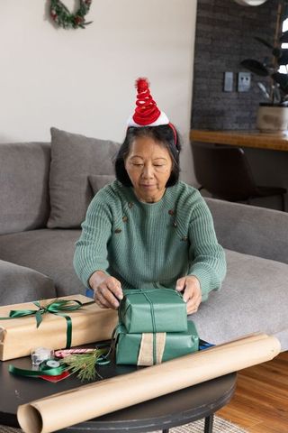 Senior Woman Wrapping Presents in Festive Living Room Setting