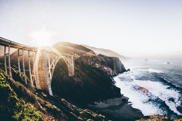 Capturing the beauty of a coastal bridge at sunrise with waves crashing against the rocky cliffs. Ideal for travel blogs, landscape photography portfolios, architecture magazines, and nature-themed promotions.