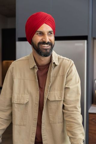 Smiling indian man with red turban in modern kitchen setting