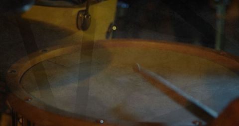 Blurry drumsticks hitting snare under warm stage lighting