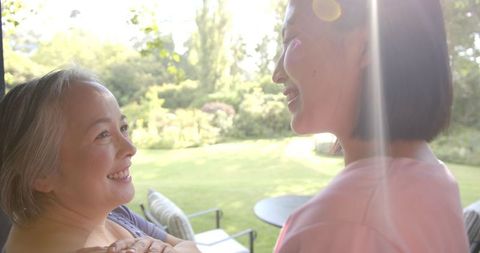 Caring asian senior with supportive caregiver in garden ambience