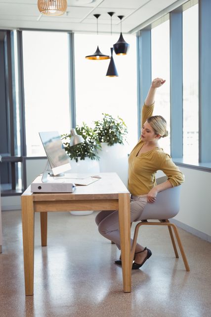 Executive stretching her hands while working at desk in office