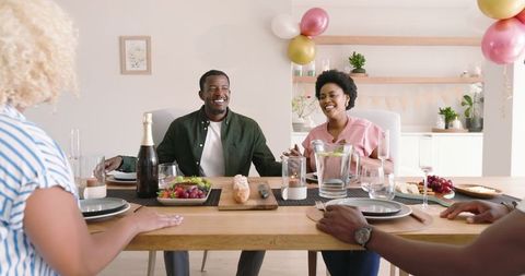 Smiling Friends Gather Around Table for Joyful Lunch