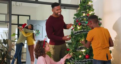 Happy Family Decorating Christmas Tree in Festive Living Room