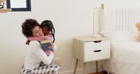 Mother and Daughter Sharing Tender Hug in Cozy Bedroom
