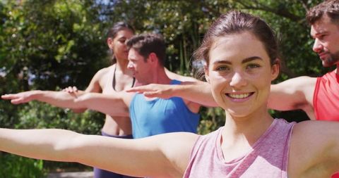 Joyful group yoga class outdoors with smiling instructor