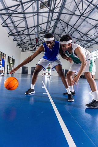 Teenage Basketball Players Competing Intensively on Blue Indoor Court